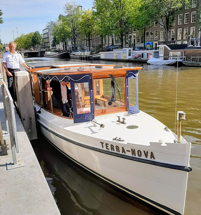 A classic Dutch canal boat tied to a dock in Amsterdam