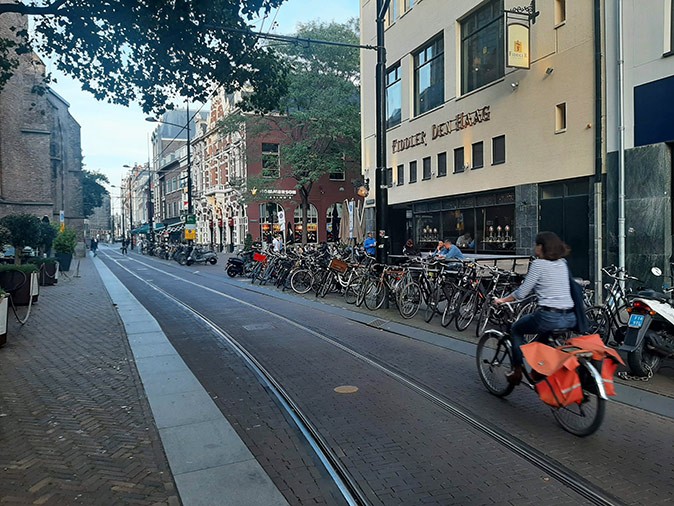 a woman on a bicycle on a city center street with lots of parked bicycles