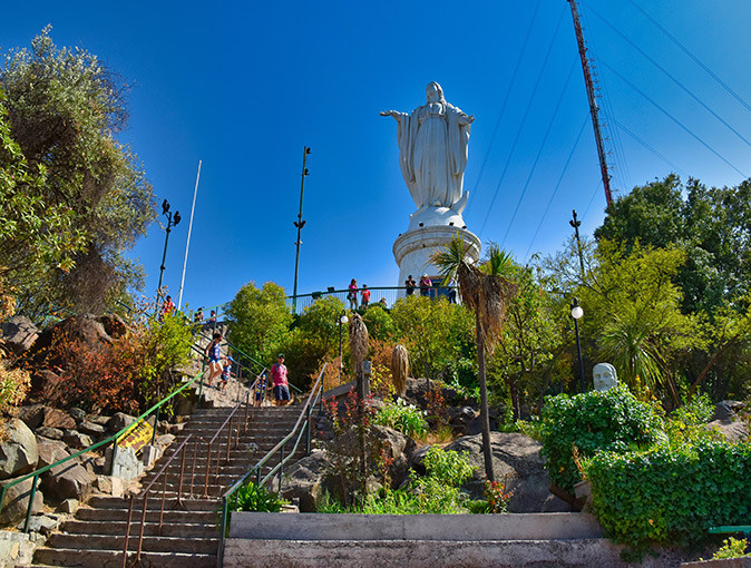 City life in Santiago Chile A city park showing greenery, steps and a large white statue, with several people