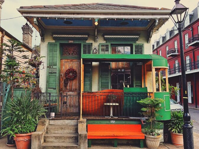 New Orleans, Louisiana a typical New Orleans house with green shutters and an orange bech in front of a wooden porch