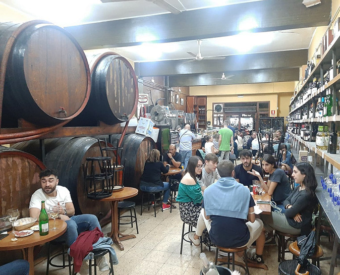 One of the best small tapas bars in Valencia A busy tapas bar showing large wooden barrels, small tables, bright light and several people