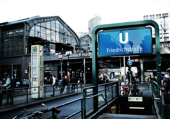 Living in Berlin, Germany Gray modern buildings with several people and the entrance to a metro station