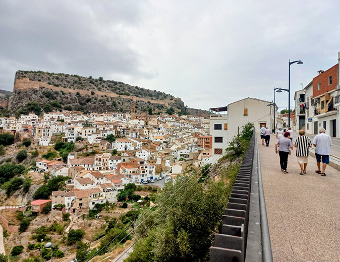 A typical Spanish mountain town with whitewashed houses and some elderly people walking in the foreground
