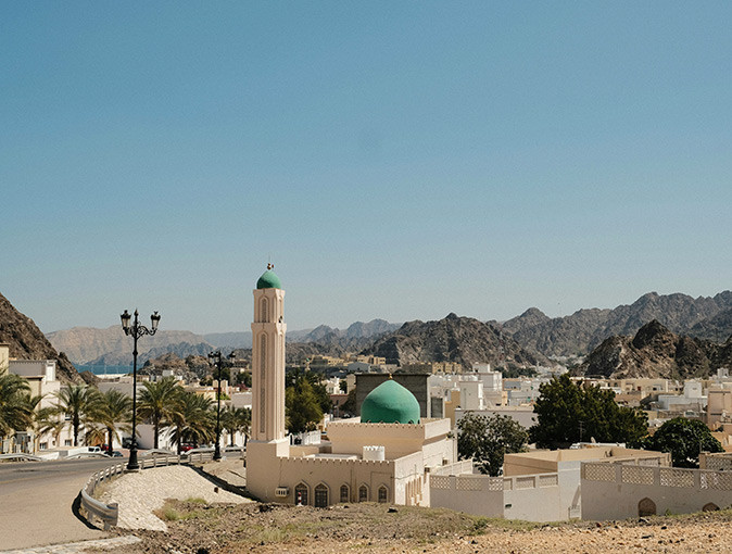 Pros and cons of living in Muscat, Oman Aerial view of Muscat showing a white mosque with a blue dome and several white houses