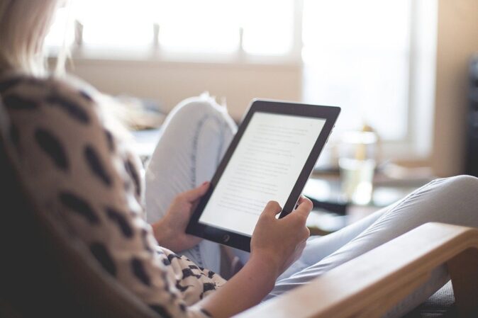woman reading a Kindle - things to do at home alone woman reading a Kindle