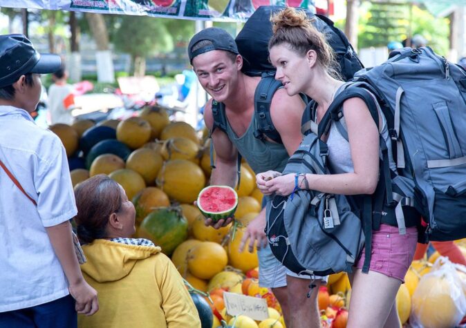 Travel makes you humble - best reasons to travel a couple buying fruit in Vietnam