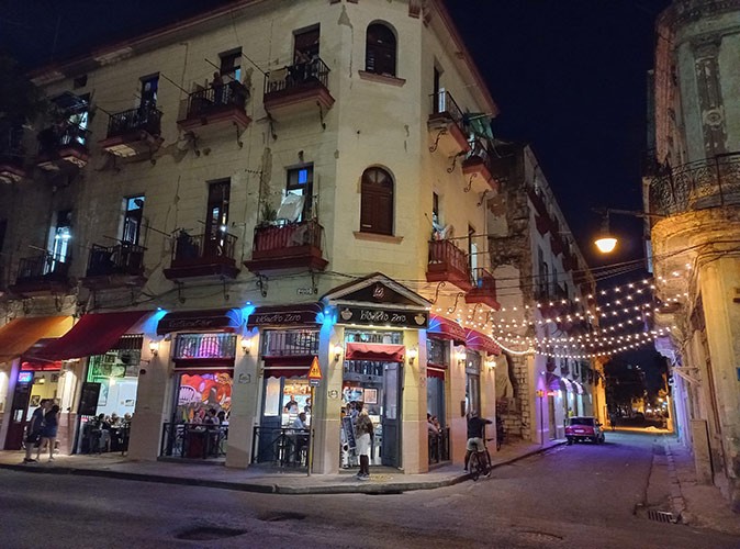 the streets of Havana at night with a cafe on the corner of an old building