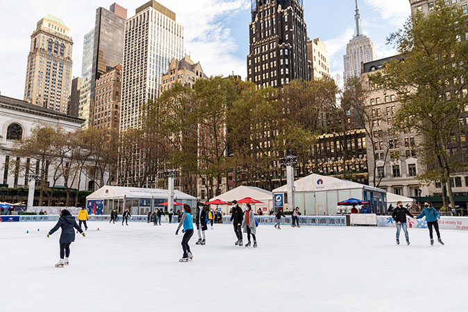 several people ice skating surrounded by highrise buildings