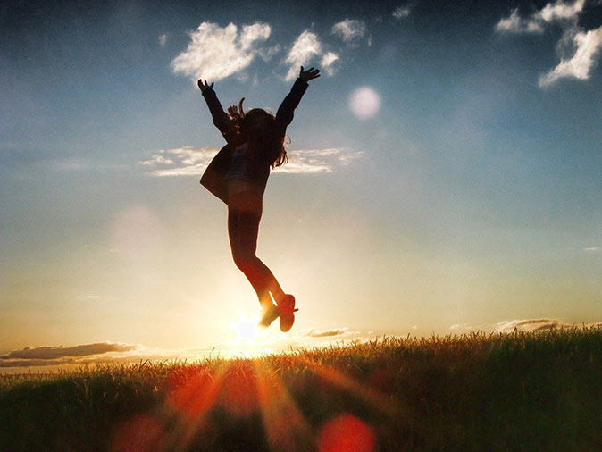 a happy person jumping into the sunset