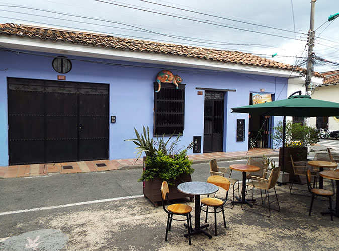 Life in Cali, Colombia purple exterior of a restaurants with several small tables and chairs on the pavement