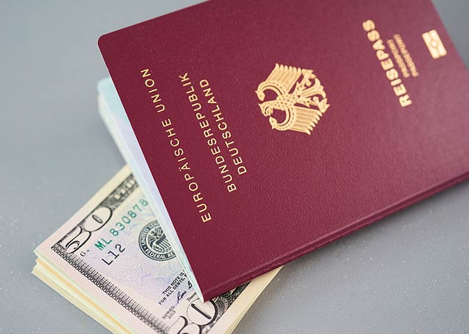 a German passport on top of US Dollar bills