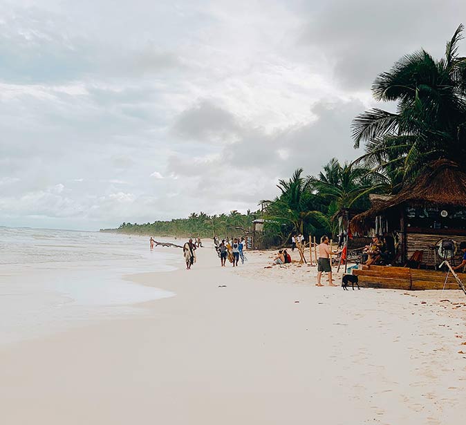 a sandy beach in Tulum with a beach bar on the right side