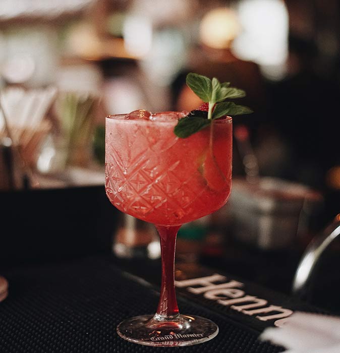 a red cocktail in a bar in Tulum with a blurred background