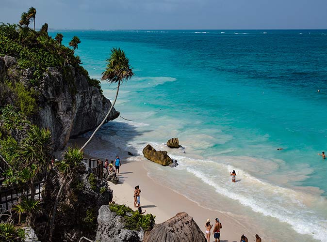 a view down to the beach in Tulum with several people on the beach