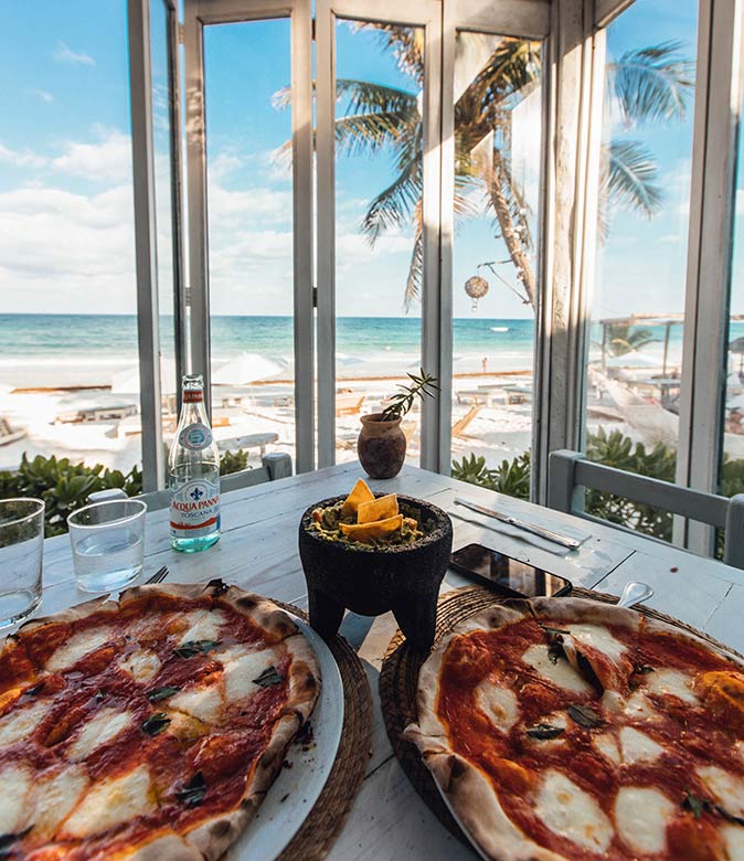 2 pizzas in a restaurant looking out onto the beach in Tulum