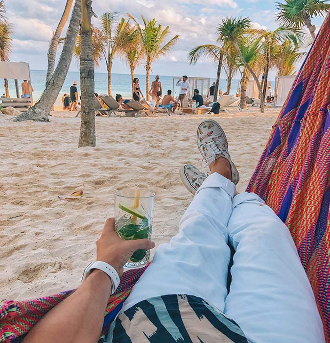 a man in a hammock holding a cocktail at Playa Paraíso