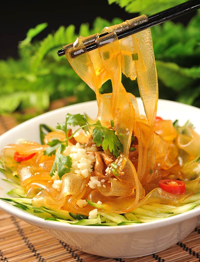 Try liangpi in Shanghai chopsticks lifting some noodles from a bowl of liangpi
