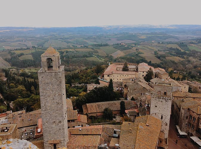 a cluster of medieval houses seen from the top, with flat countryside in the background
