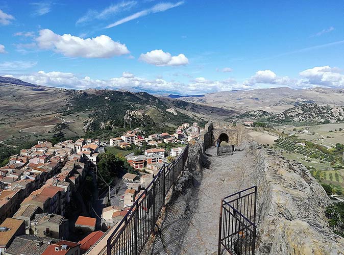 Sperlinga, one of the small towns in Italy to visit a cluster of small houses surrounded by hills with a blue sky