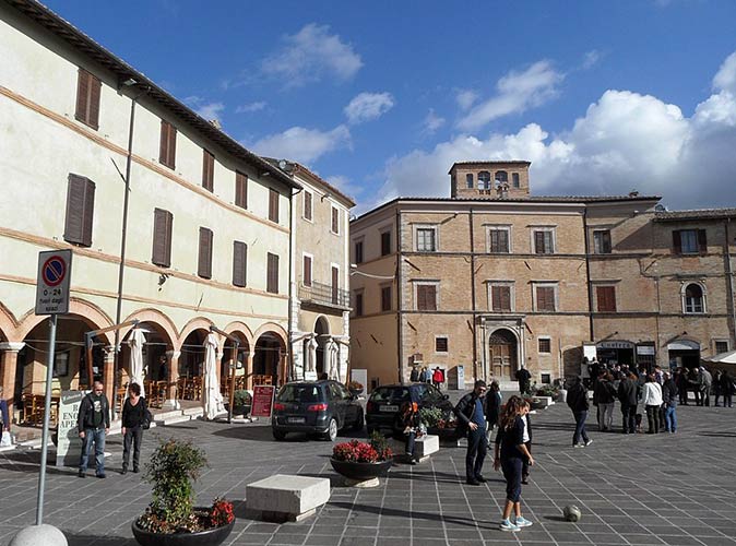 Montefalco is one of the beautiful places to visit in Italy a lot of people on a town square in Italy surrounded by large historic buildings