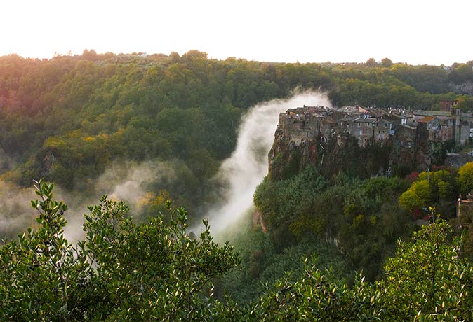 Calcata is one of the most beautiful small towns in Italy a cliff with houses surrounded by a green valley with low hanging mist