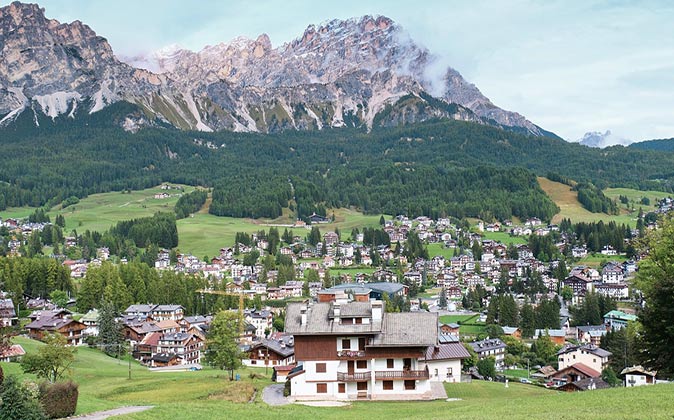 houses scattered around a green valley surrounded by high mountains