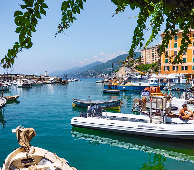Camogli, a charming fishing village in Italy to visit small boats in very blue water in the port of a small town in Italy