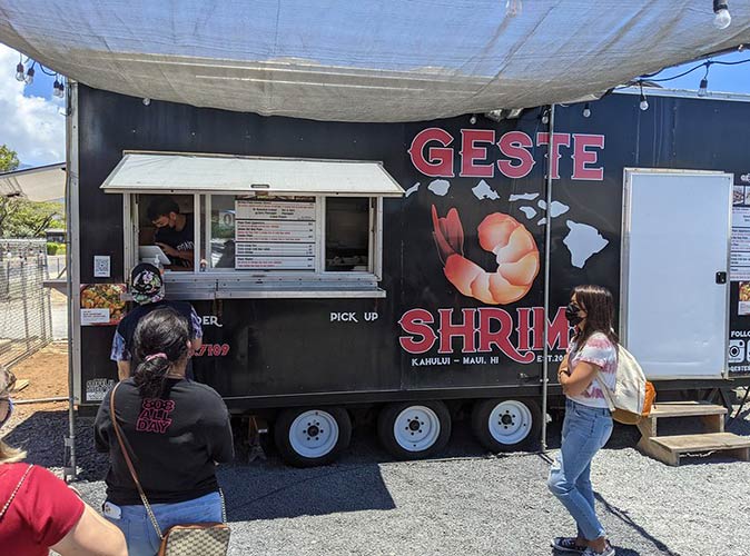 people waiting in line in front of a black food truck