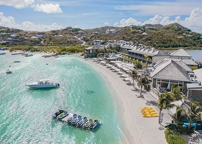 Le Barthélemy Hotel & Spa, a luxury hotel in the Caribbean worth the money a Caribbean resort set on a white sandy beach with clear water, jet skis and boats in the foreground