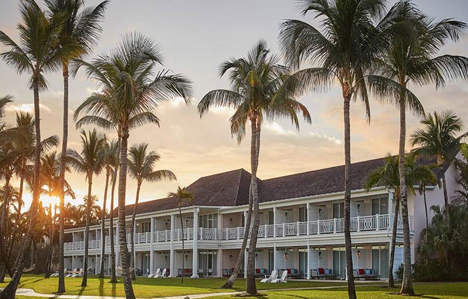 The Ocean Club, one of the best luxury resorts in the Caribbean a luxury, colonial-style building surrounded by palmtrees, with the sun setting