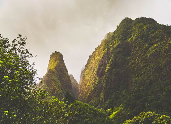 very large rock formations completely covered in greenery with a moody sky