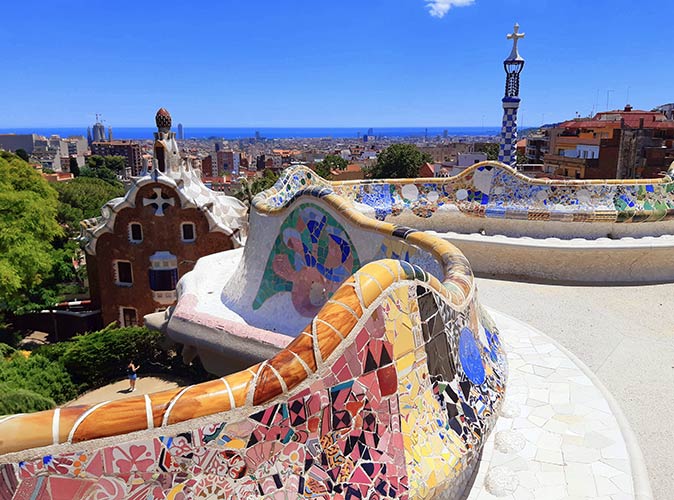colorfully decorated benches with a view of the city and sea in the background