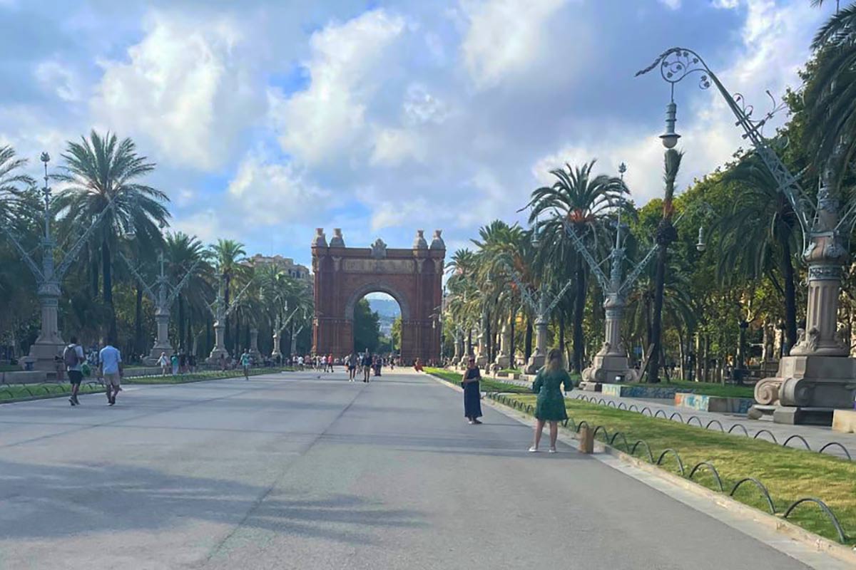 a large manmade arch structure with people on a wide road going through the arch