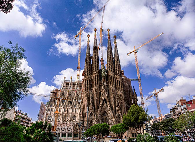 a large basilica surrounded by trees and several cranes