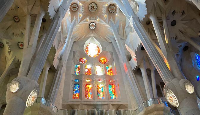 the inside of a basilica with tall white pillars and stained glass