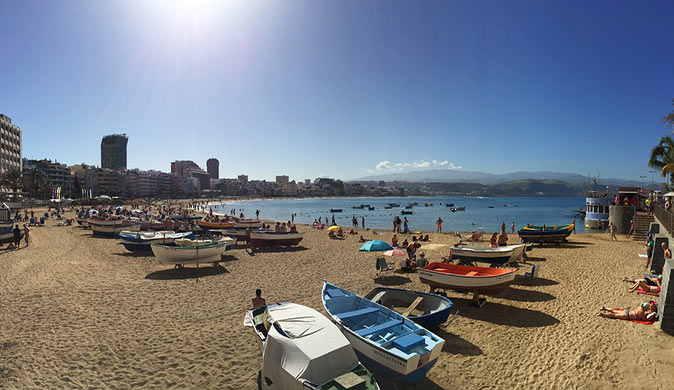 a sandy beach with various boats on the beach and a lot of people