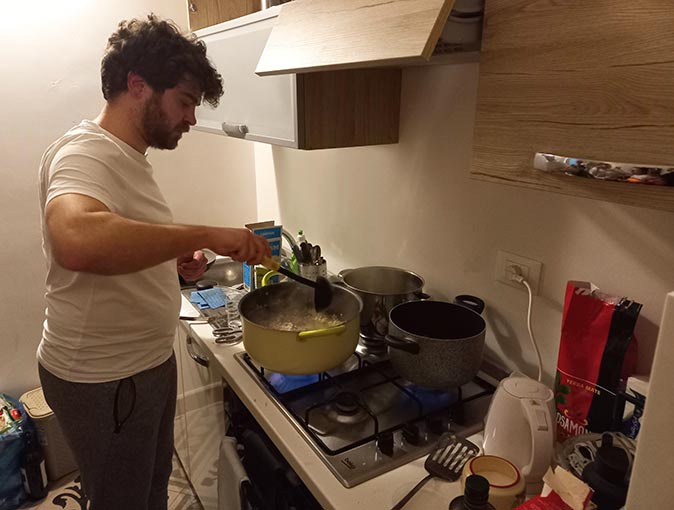 a man cooking risotto in a small kitchen