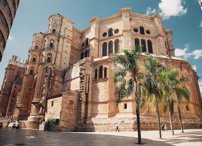 a large brown cathedral with several palm trees