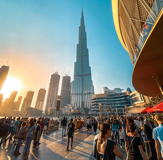a crowd on a pavement with the Dubai skyline in the background