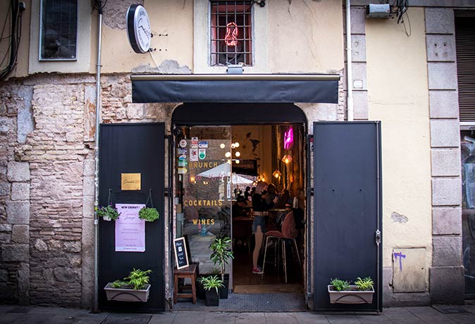 a woman behind half opened glass doors which form the entrance to a restaurant in Barcelona