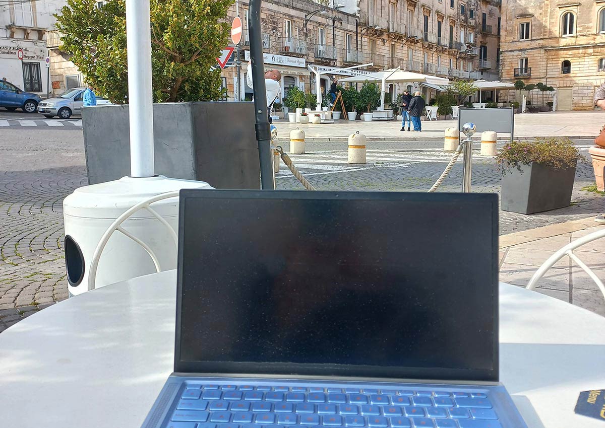A laptop used to work remotely from Italy with a typical Italian square in the background
