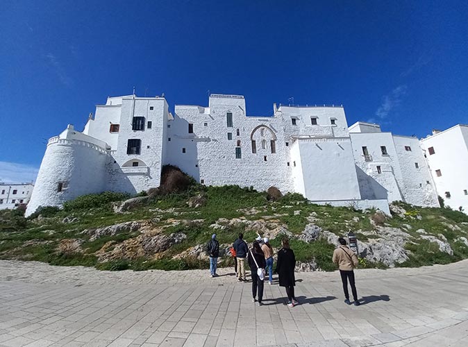 a group of people standing in front of whitewashed buildings with a blue sky