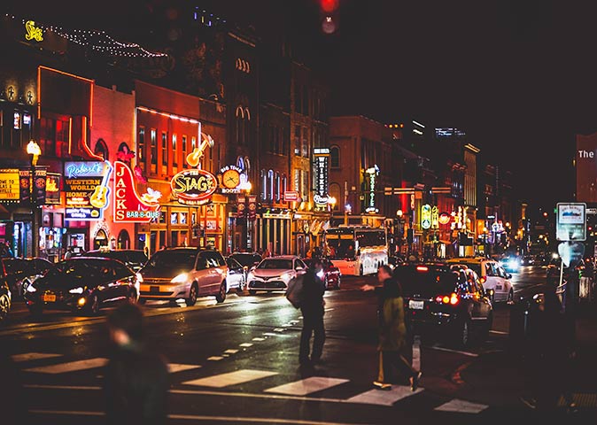a street at night with many neon lights and cars