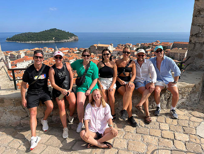 A group of people posing for a picture with a Croatian town in the background