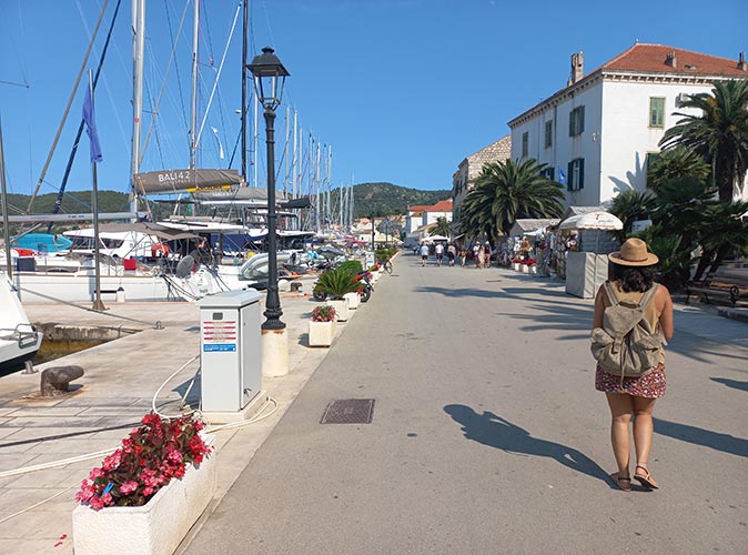 A woman walking on a boardwalk lined with yachts
