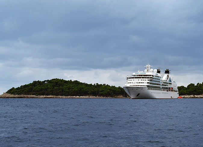 A cruise ship surrounded by water with land in the background