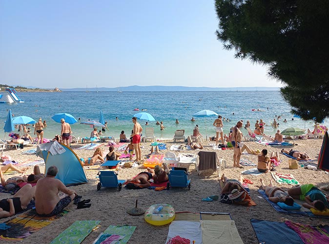 A crowded beach with people, towels and umbrellas