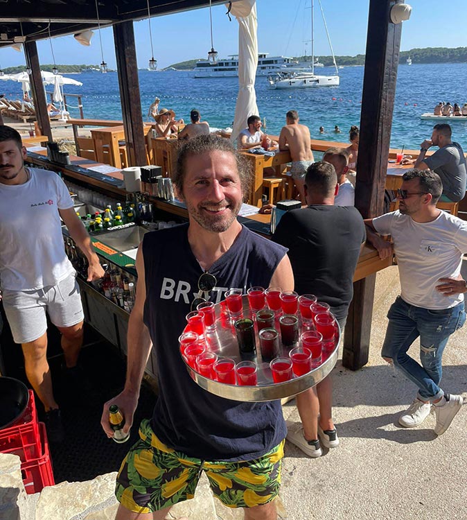 A man hoding a tray of shots in a beach bar