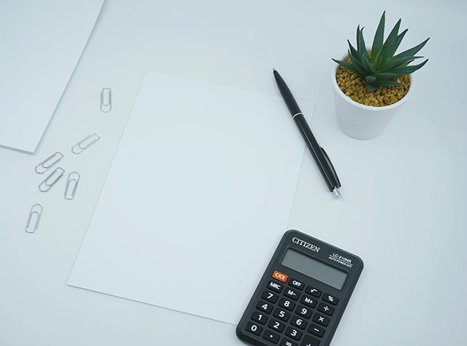 a white sheet of paper, a pen, a calculator and a plant