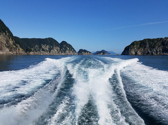 waves behind a boat with mountains in the background